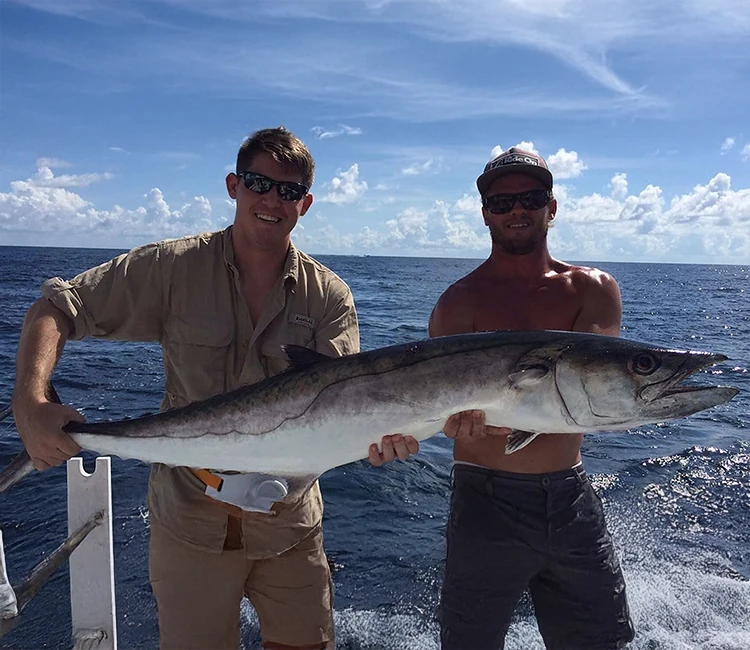 Two fishers showing a fish caught in the Destin waters.