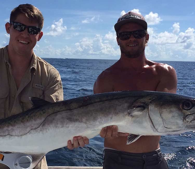Two fishers showing a fish caught in the Destin waters.