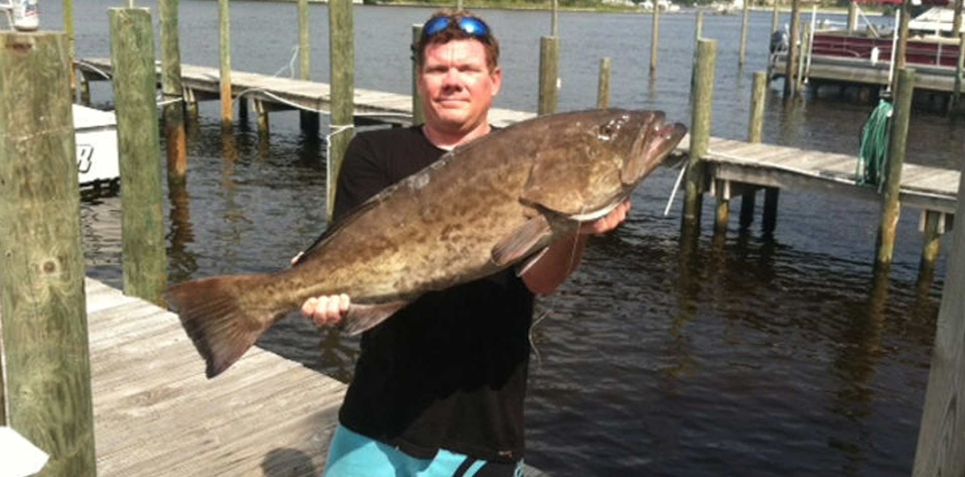 Man holding up grouper caught on fishing trip.