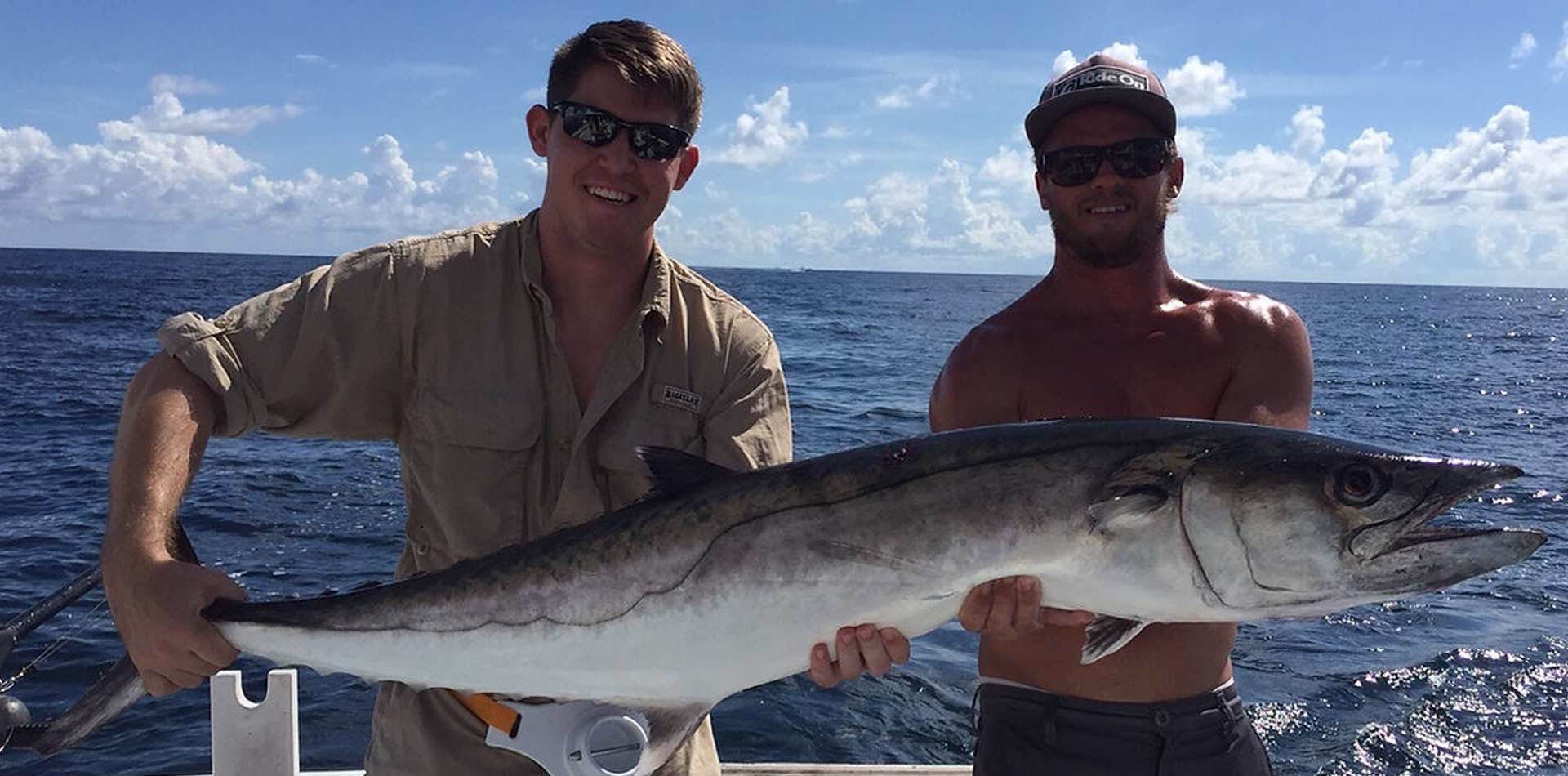 Two fishers showing a fish caught in the Destin waters.