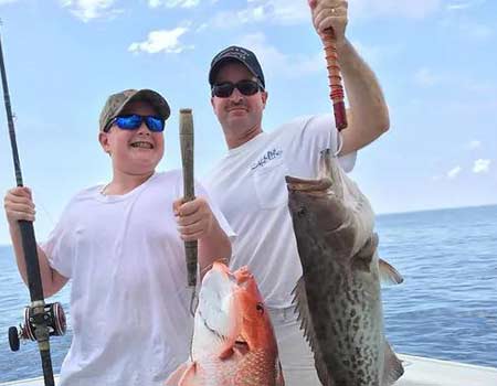 Adult and youth holding up their caught snapper. 