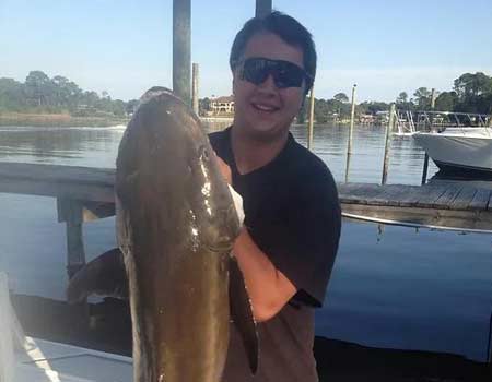  Man aboard boat holding up his catch.