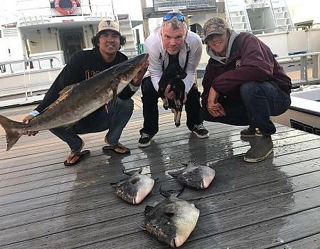  Three adult men with their caught fish on the dock.