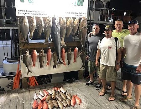  Team of fishemen pose at night on the dock with their catch.